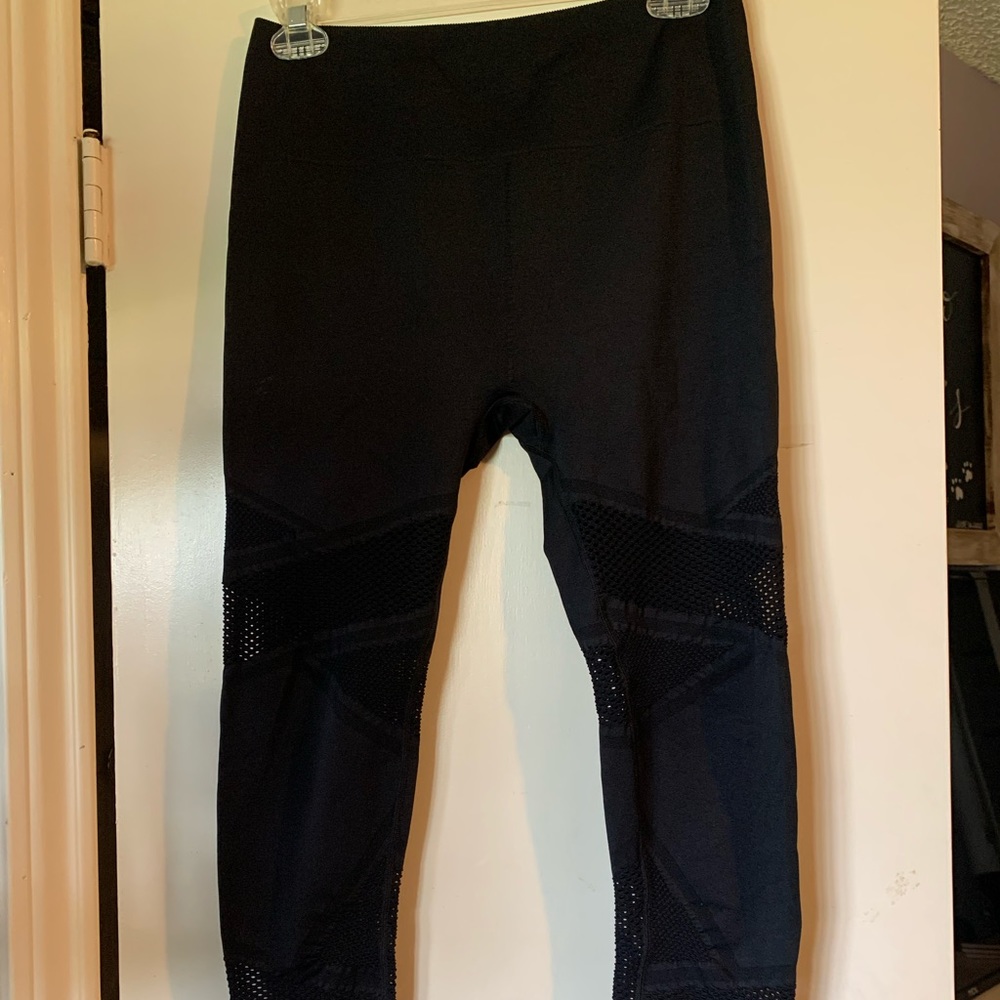 7/8th length, black leggings with a textured hole pattern down the legs.